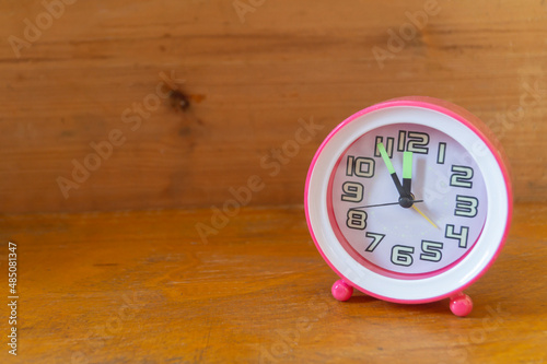 A round clock stands on a wooden shelf