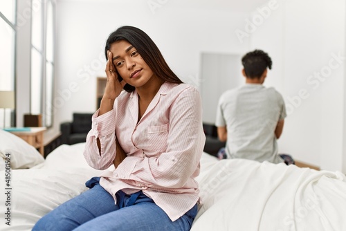 Young couple with serious expression on trouble sitting on the bed at bedroom.