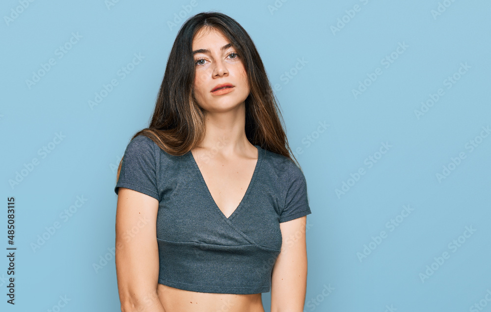 Young beautiful teen girl wearing casual crop top t shirt relaxed with serious expression on face. simple and natural looking at the camera. Young beautiful teen girl wearing casual crop top t shirt relaxed with serious expression on face. simple and natural looking at the camera.