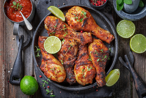 Murais de parede Spicy roasted chicken leg served with lime and sauces.