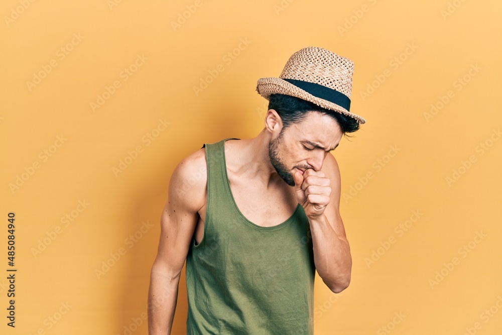Young hispanic man wearing summer hat feeling unwell and coughing as symptom for cold or bronchitis. health care concept. Young hispanic man wearing summer hat feeling unwell and coughing as symptom for cold or bronchitis. health care concept.