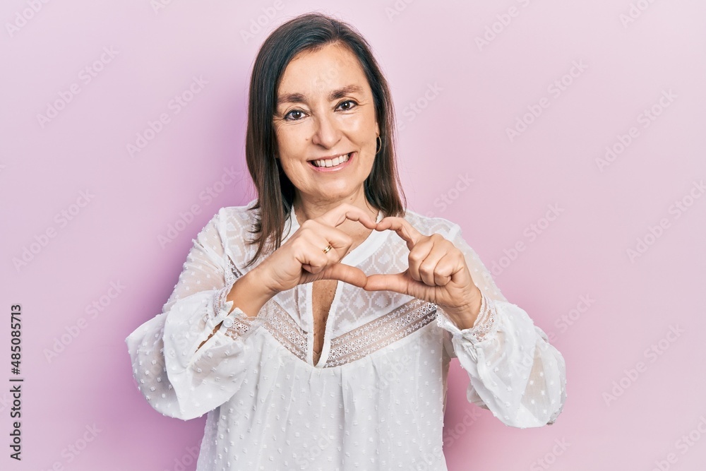 Middle age hispanic woman wearing casual clothes smiling in love doing heart symbol shape with hands. romantic concept. Middle age hispanic woman wearing casual clothes smiling in love doing heart symbol shape with hands. romantic concept.