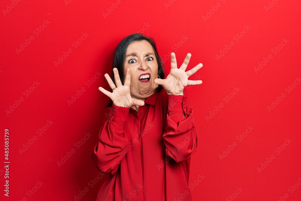 Middle age hispanic woman wearing casual clothes afraid and terrified with fear expression stop gesture with hands, shouting in shock. panic concept. Middle age hispanic woman wearing casual clothes afraid and terrified with fear expression stop gesture with hands, shouting in shock. panic concept.