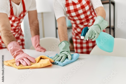 Young caucasian couple cleaning table using rag and diffuser at home.