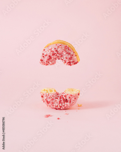 Minimal composition with pink donut cutted in half against pastel pink background. Creative copy space.