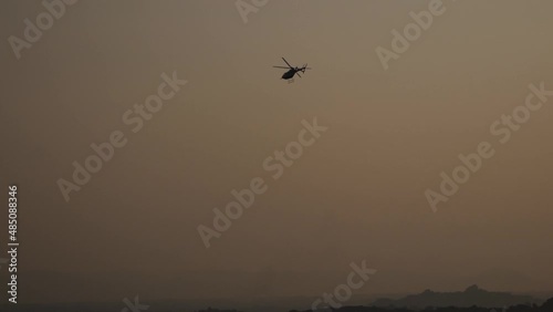 silhouette of helicopter flight on sunset over valley in India, Hampi