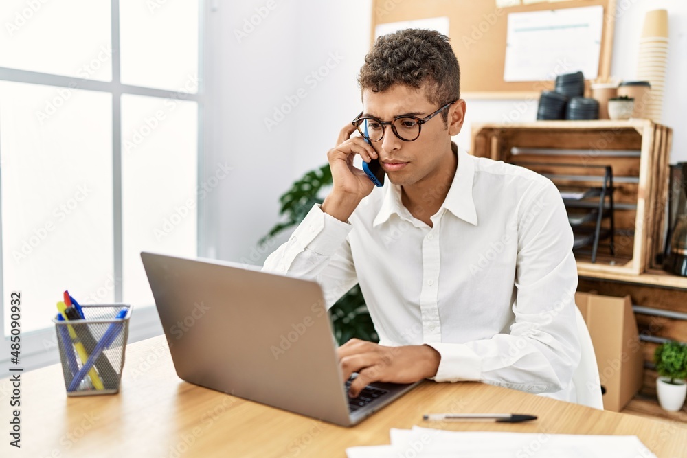 Young hispanic man working speaking on the phone at business office