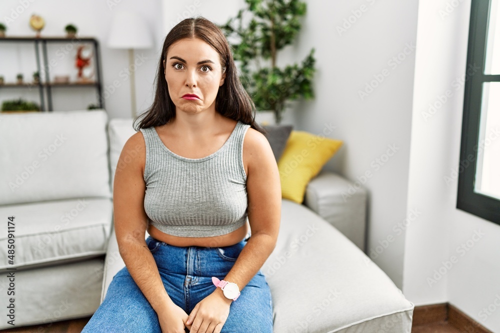 Young brunette woman sitting on the sofa at home depressed and worry for distress, crying angry and afraid. sad expression. Young brunette woman sitting on the sofa at home depressed and worry for distress, crying angry and afraid. sad expression.