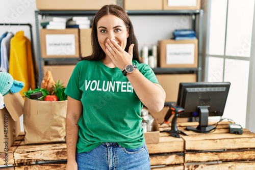 Schilderij op canvas Young brunette woman wearing volunteer t shirt at donations stand laughing and e