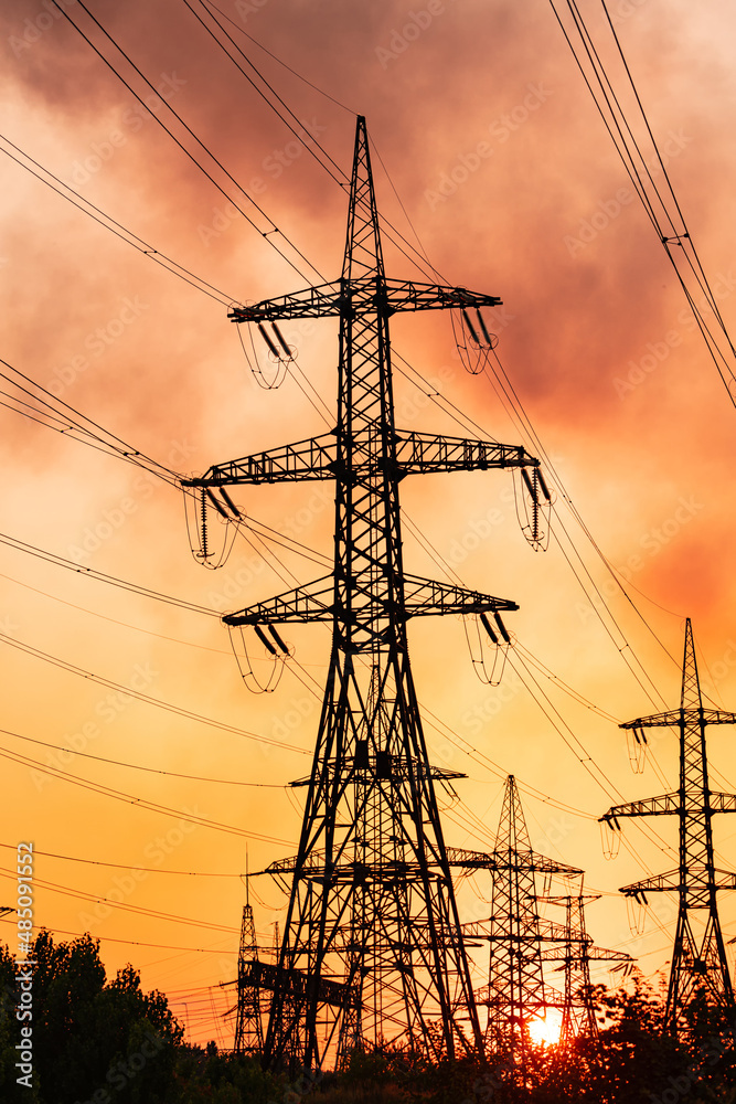 Metal construction silhouette. Electrical supply tower shadows on orange sunset.