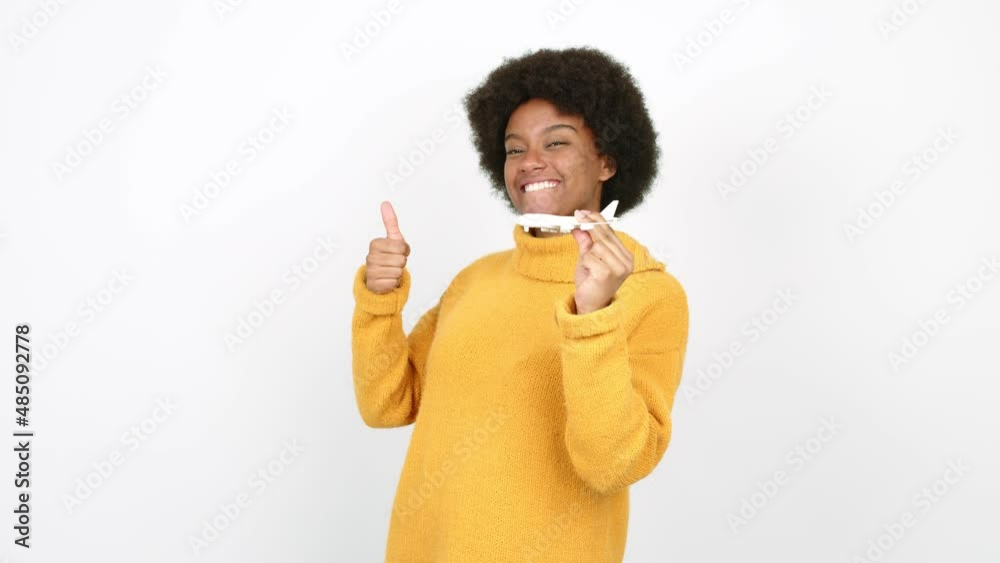 Young African American woman holding a toy airplane and with thumb up over isolated background Young African American woman holding a toy airplane and with thumb up over isolated background