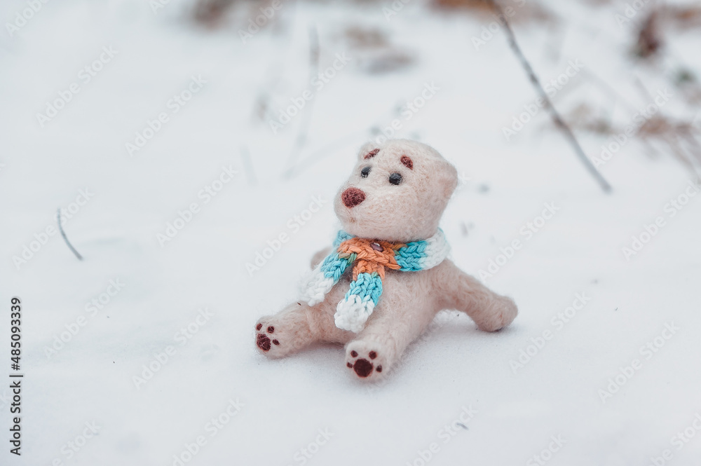 an isolated toy polar bear in a scarf sits on the snow in the winter field an isolated toy polar bear in a scarf sits on the snow in the winter field