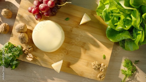 Commercial pack shot with cheese, grapes, walnut and greens on serving board