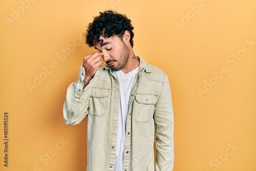 Young hispanic man wearing casual clothes tired rubbing nose and eyes feeling fatigue and headache. stress and frustration concept.