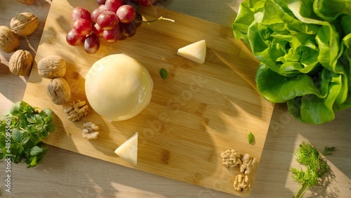 Commercial pack shot with cheese, grapes, walnut and greens on serving board