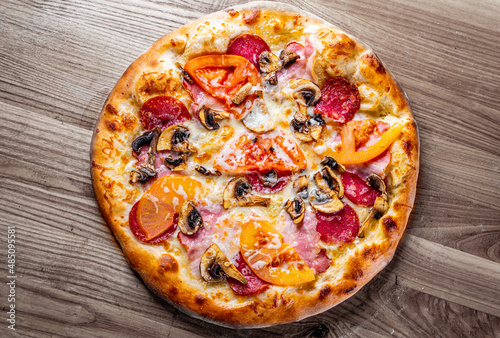 pizza with Mozzarella cheese, ham, mushrooms, salami. Italian pizza on wooden table background
