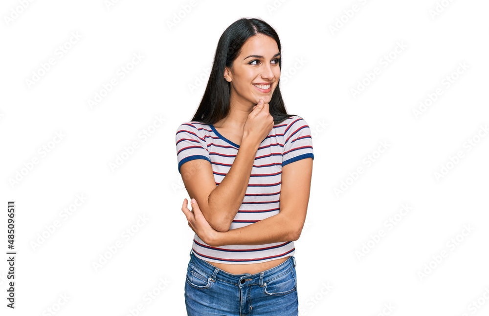 Young hispanic girl wearing casual striped t shirt with hand on chin thinking about question, pensive expression. smiling with thoughtful face. doubt concept. Young hispanic girl wearing casual striped t shirt with hand on chin thinking about question, pensive expression. smiling with thoughtful face. doubt concept.