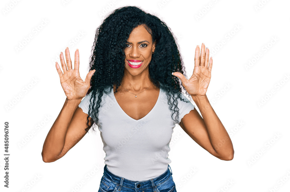 Middle age african american woman wearing casual white t shirt showing and pointing up with fingers number ten while smiling confident and happy. Middle age african american woman wearing casual white t shirt showing and pointing up with fingers number ten while smiling confident and happy.