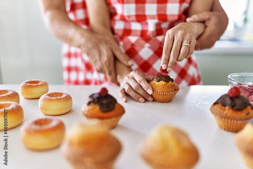 Couple cooking muffins at the kitchen.