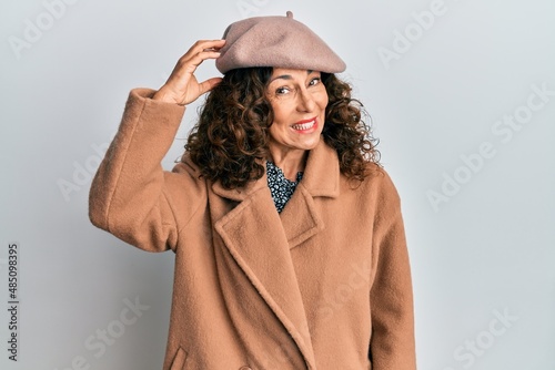 Middle age hispanic woman wearing french look with beret confuse and wonder about question. uncertain with doubt, thinking with hand on head. pensive concept.