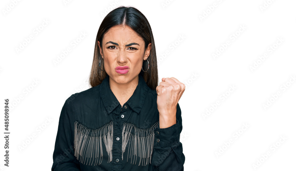 Young hispanic woman wearing casual clothes angry and mad raising fist frustrated and furious while shouting with anger. rage and aggressive concept. Young hispanic woman wearing casual clothes angry and mad raising fist frustrated and furious while shouting with anger. rage and aggressive concept.