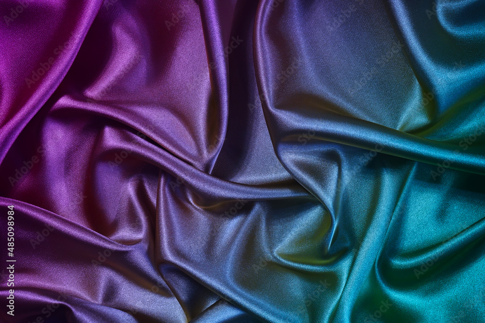 Fototapeta premium Purple green silk satin background. Gradient. Folds on shiny fabric surface. Beautiful pink teal background with space for design.