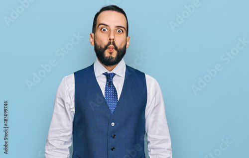 Young man with beard wearing business vest making fish face with lips, crazy and comical gesture. funny expression.