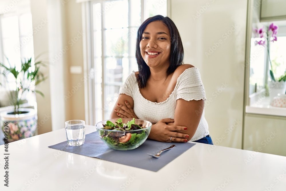 Young hispanic woman eating healthy salad at home with a happy and cool smile on face. lucky person.