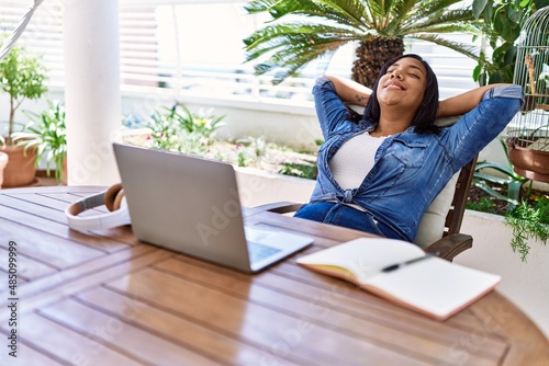 Hispanic brunette woman resting after studying with laptop at the terrace