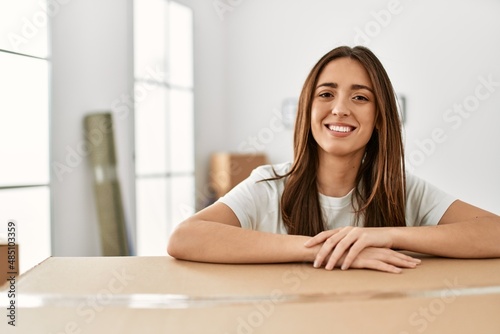 Young hispanic woman smiling confident leaning on package at new home