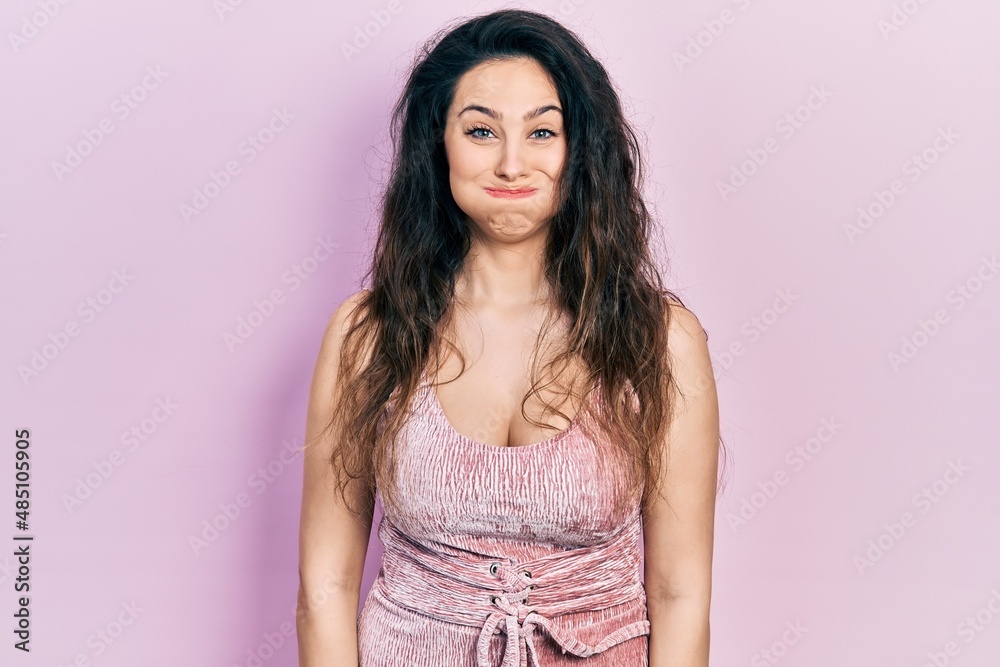 Young hispanic woman wearing casual clothes puffing cheeks with funny face. mouth inflated with air, crazy expression. Young hispanic woman wearing casual clothes puffing cheeks with funny face. mouth inflated with air, crazy expression.