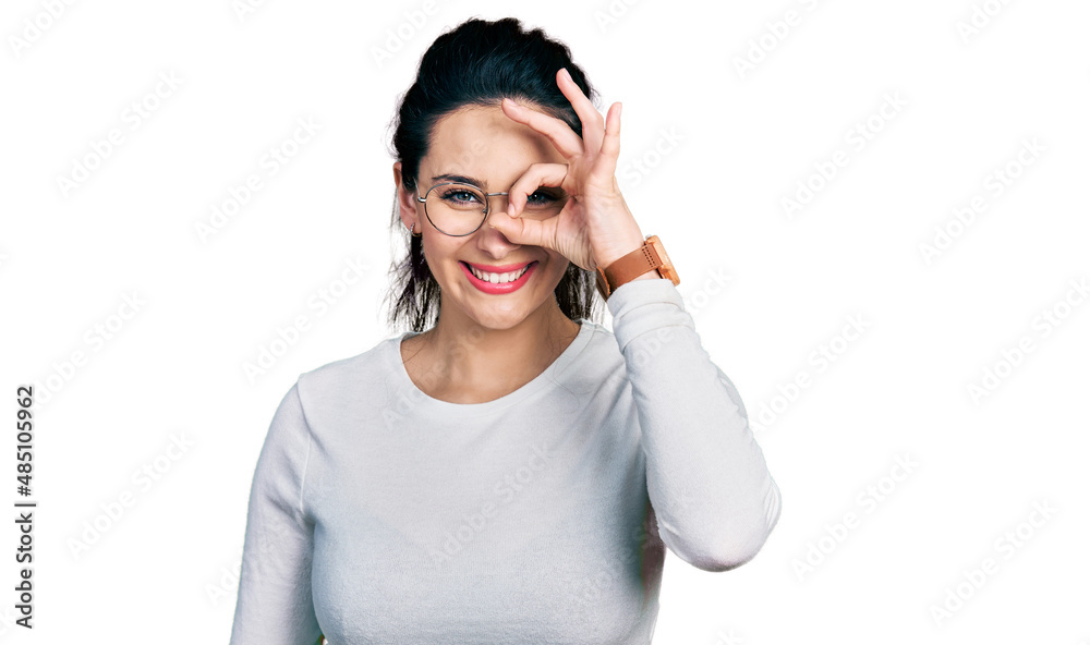 Young hispanic woman wearing casual clothes doing ok gesture with hand smiling, eye looking through fingers with happy face. Young hispanic woman wearing casual clothes doing ok gesture with hand smiling, eye looking through fingers with happy face.