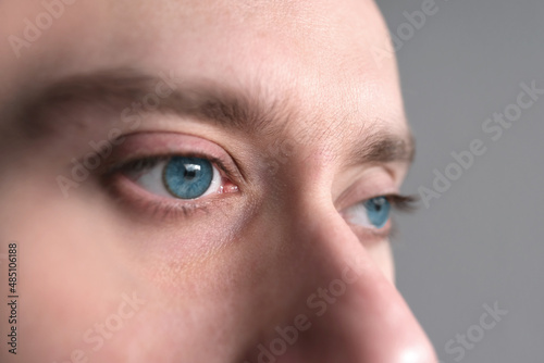 close up part of male face, guy, young blue-eyed man 25-30 years old, human eye looking to side, concept of surveillance, peeping, tracking, vision examination, cosmetic procedures, skin health