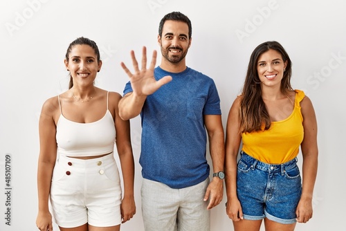 Group of young hispanic people standing over isolated background showing and pointing up with fingers number five while smiling confident and happy.