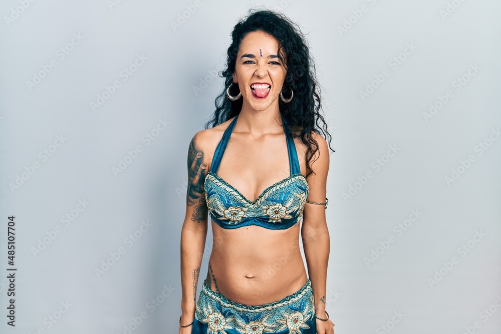 Young woman wearing bindi and traditional belly dance clothes sticking tongue out happy with funny expression. emotion concept. Young woman wearing bindi and traditional belly dance clothes sticking tongue out happy with funny expression. emotion concept.