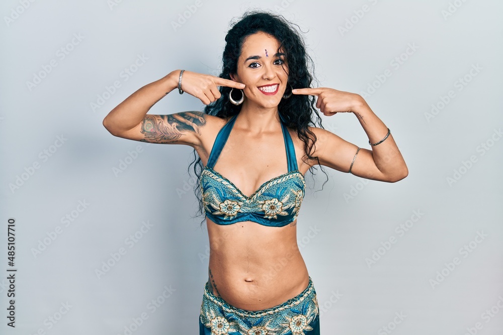 Fototapeta premium Young woman wearing bindi and traditional belly dance clothes smiling cheerful showing and pointing with fingers teeth and mouth. dental health concept.