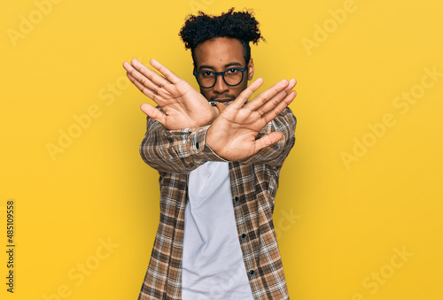 Young african american man with beard wearing casual clothes and glasses rejection expression crossing arms and palms doing negative sign, angry face photo