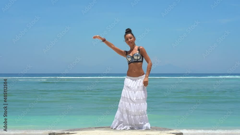 Gorgeous girl in long skirt dancing, meditating elegance moves, spiritual dance in front of wavy ocean water 