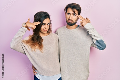 Young hispanic couple wearing casual clothes shooting and killing oneself pointing hand and fingers to head like gun, suicide gesture. © Krakenimages.com