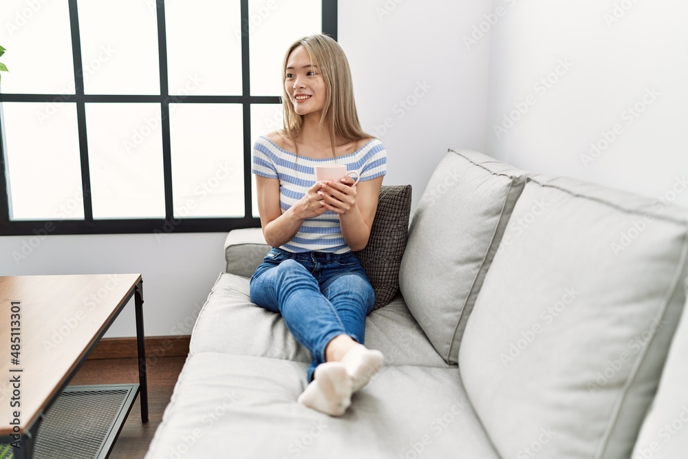 Young chinese woman smiling confident drinking coffee at home