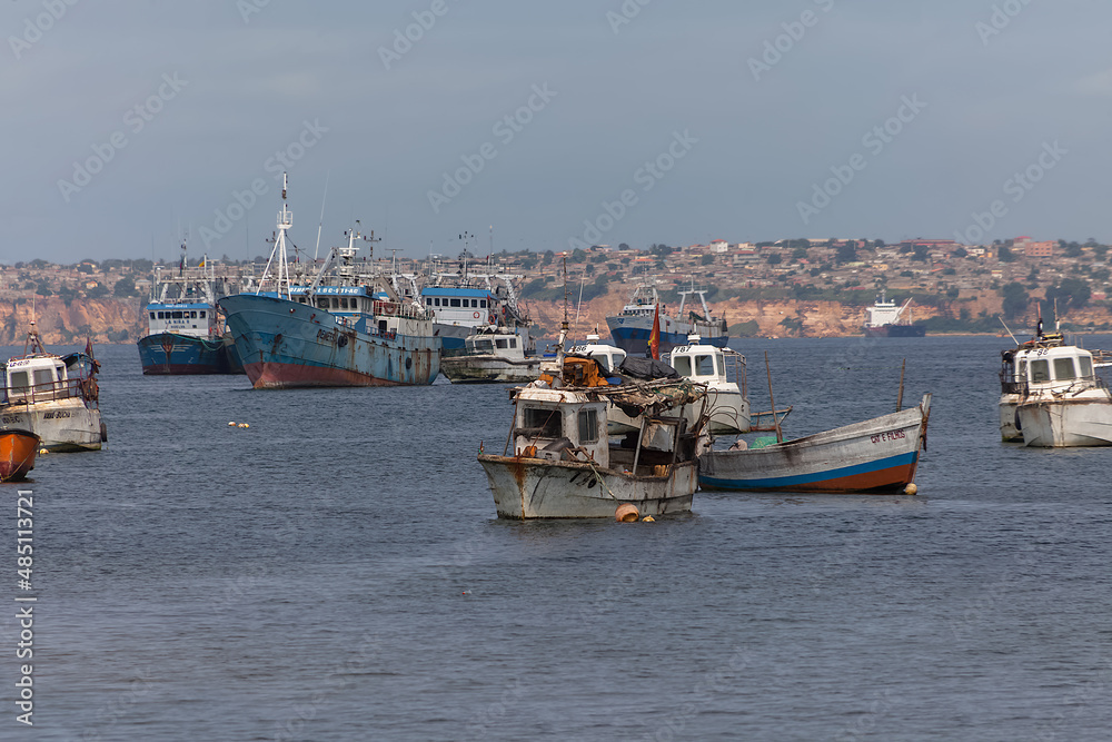 View of fishing boats on the coast of Luanda city, Luanda Bay, with Port of Luanda, transport ships and containers in the background, Angola View of fishing boats on the coast of Luanda city, Luanda Bay, with Port of Luanda, transport ships and containers in the background, Angola