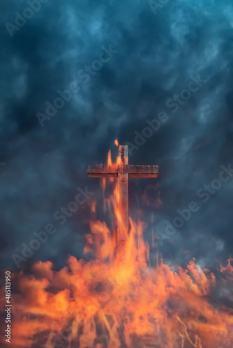 Christian cross in red clouds and fire against a stormy sky.