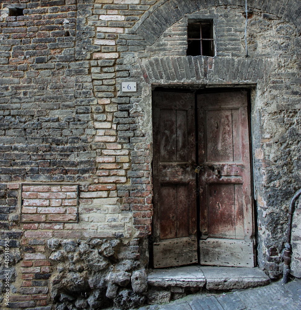 old wall with weathered door in Siena, Italy