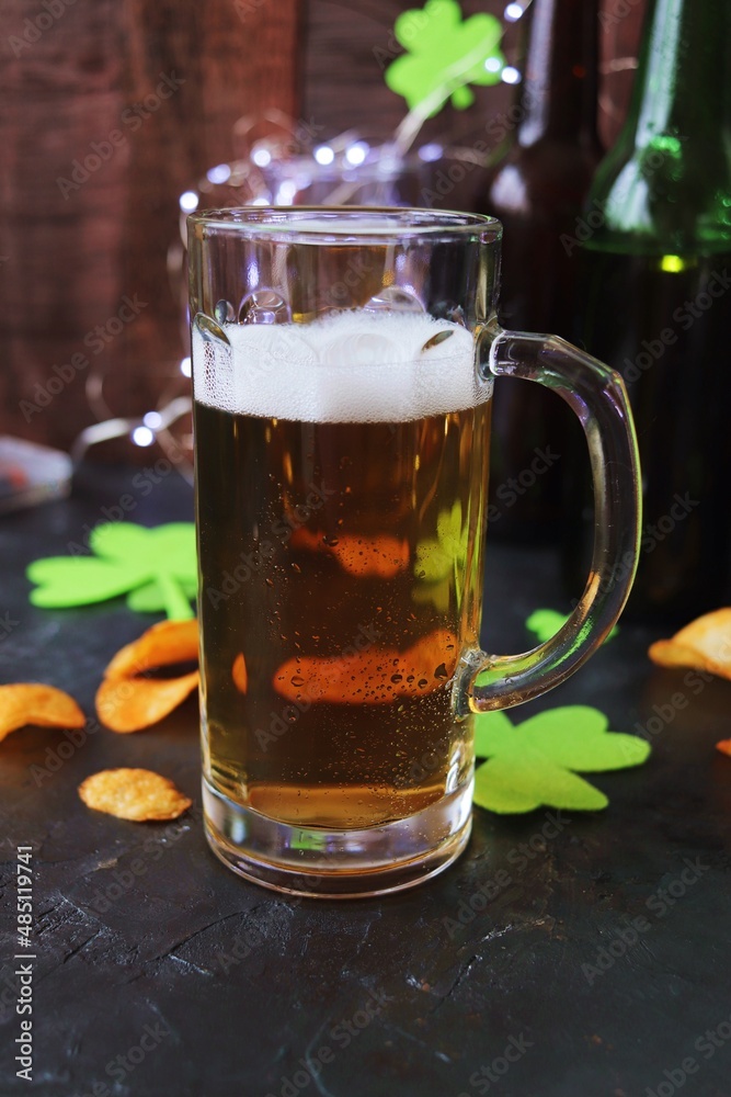 Patrick Day, foamy beer in glass mugs and a bottle, chips, golden coins and a green shamrock on a wooden background, party, congratulation, postcard Patrick Day, foamy beer in glass mugs and a bottle, chips, golden coins and a green shamrock on a wooden background, party, congratulation, postcard