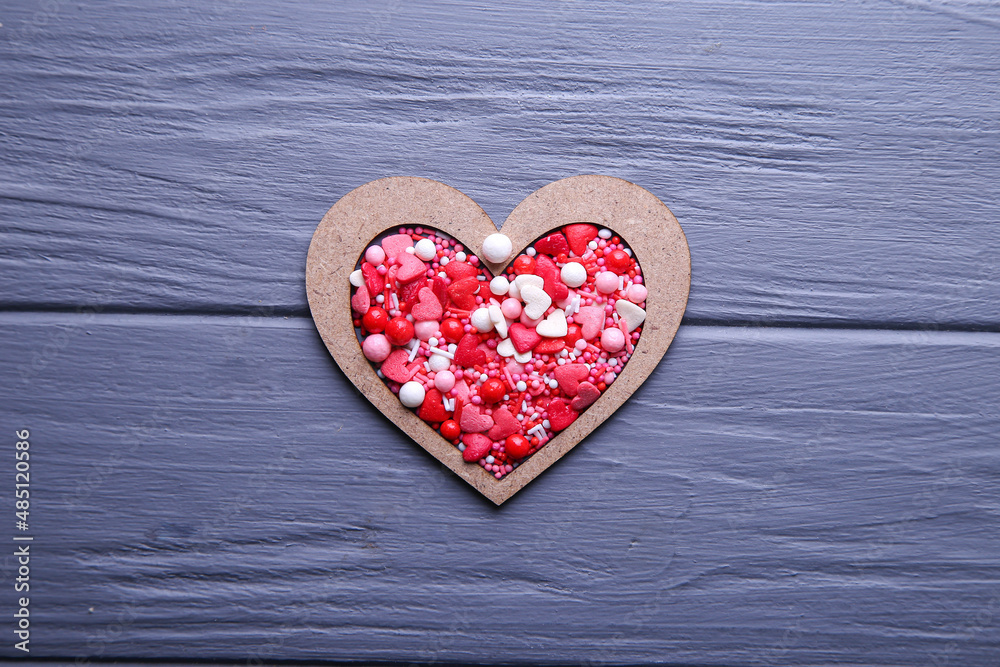 Obraz premium Heart of candy in wooden form on a grey background