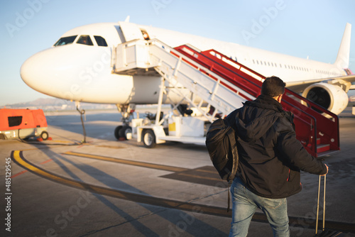 Passenger walking with his suitcases towards the plane