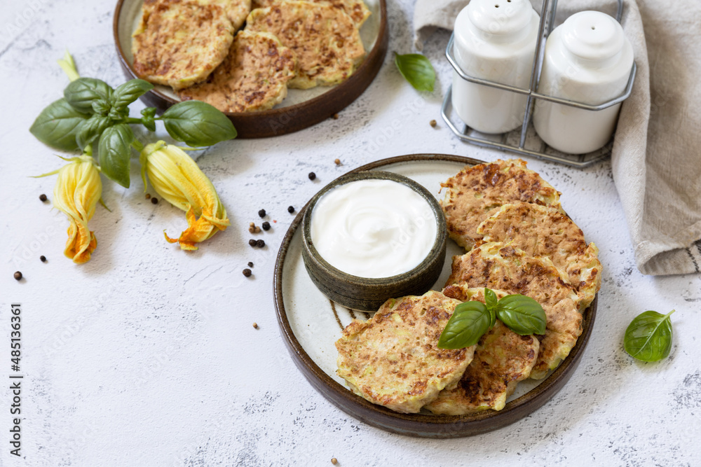 Zucchini fritters. Vegetarian zucchini pancakes with cheese, served with sour cream on a rustic wooden table. Healthy food, low calories keto dieting meal. Copy space.