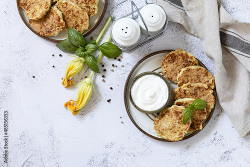 Zucchini fritters. Vegetarian zucchini pancakes with cheese, served with sour cream on a rustic wooden table. Healthy food, low calories keto dieting meal. Top view flat lay background. Copy space.