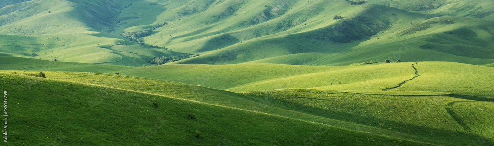 Green hillsides in the evening light, spring greenery, panoramic view