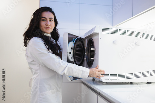 Woman medical worker opens autoclave door. Sterilization of a medical instrument photo